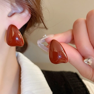 Detailed view of teardrop enamel stud earrings in vintage reddish brown with gold trim
