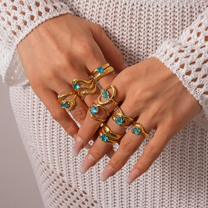 Ensemble de bagues géométriques dorées avec zircons bleus porté sur fond en maille blanche