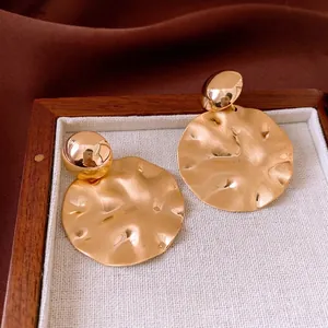 Retro brushed gold irregular disc earrings with silver needle on dark velvet