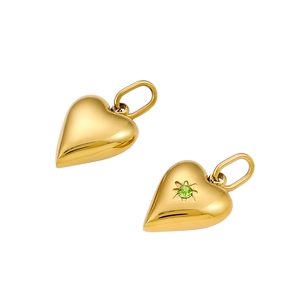 Detail of heart-shaped gold steel pendants with green gemstone and polished surface