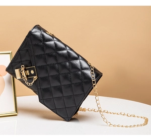 Detail of black quilted leather crossbody bag with elegant gold chain and secure lock