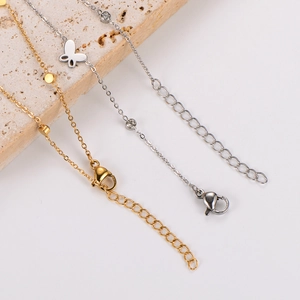 Close-up of gold disc anklet and silver butterfly charm with cubic zirconia stones