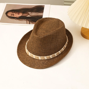Deep brown fedora straw hat with decorative woven band on a minimalist white surface