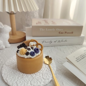 Caramel cake scented candle with realistic cream and fruit toppings on lace coaster