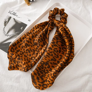 Detailed shot of leopard print satin hair scrunchie with long ribbon on white fabric