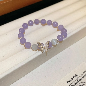 Détail macro du bracelet perlé violet avec charm papillon en cristal et perles d'opale