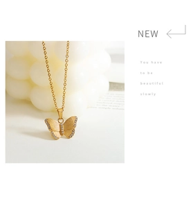 Detail of a golden butterfly pendant with sparkling zircons on a delicate link chain