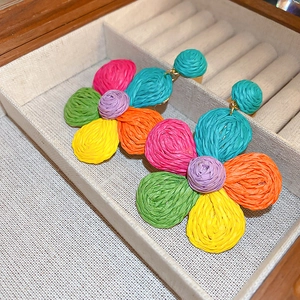 Macro shot of colorful woven raffia flower earrings with intricate braided texture in jewelry box