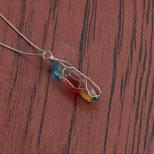 Detail of rainbow resin pillar necklace with intricate silver wire wrapping on wood