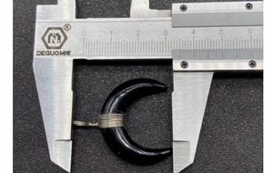 Caliper measuring the 3.4cm width of a black crescent moon horn wire wrapped pendant