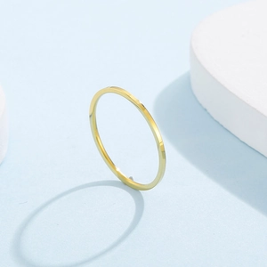 Detailed close-up of a minimalist golden polished stainless steel slim ring on stone