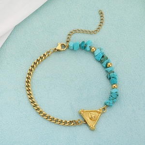 Golden chain bracelet detail with turquoise beads and engraved triangle eye pendant