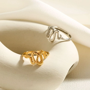 Detailed view of snake-shaped gold and silver rings with intricate scales on stone base