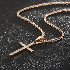 Détail d'un pendentif croix en or rose et acier inoxydable avec cristaux sertis