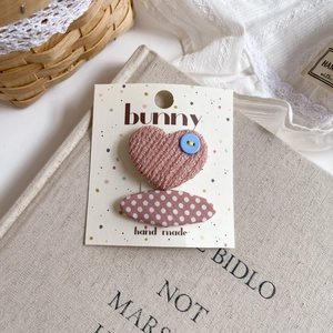Detail of pink fabric hair clips with heart and polka dot patterns on a display card