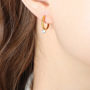 Golden huggie hoop earrings with sparkling round zircon pendant on a female model