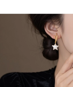 Macro shot of gold-plated star tassel earrings with zircons on a female model
