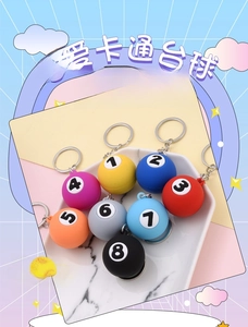 Set of eight colorful billiard ball keychains with numbers on a marble tray