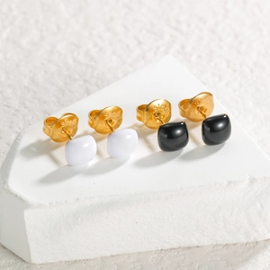 Gros plan de boucles d'oreilles carrées sur pierre avec gravure s.steel et texture