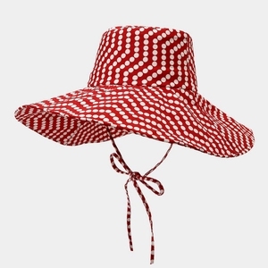 Dettaglio di un cappello da sole rosso a pois bianchi con nastri in cotone regolabili
