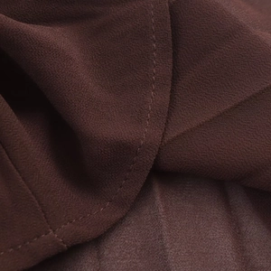 Detailed macro view of dark brown pleated chiffon fabric with high-quality hemmed edges