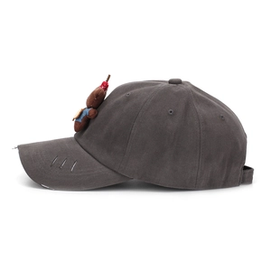 Close-up of charcoal grey distressed baseball cap featuring a cute bear plush attachment