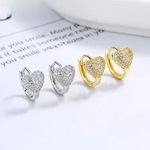 Macro shot of gold and silver heart-shaped hoop earrings with sparkling zircon stones