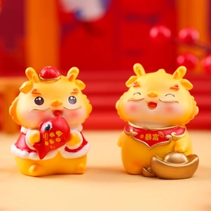 Detail view of two yellow resin dragon figurines with golden ingot and fish symbols
