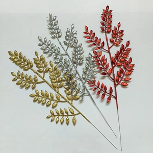 Dettaglio di foglie artificiali glitterate in oro, argento e rosso per decoro natalizio
