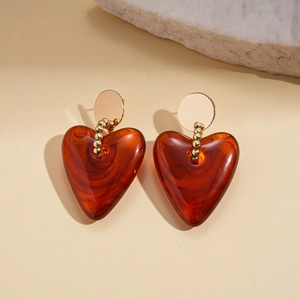 Detailed close-up of amber resin heart pendants with golden beaded link earrings