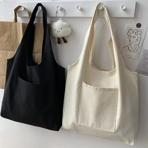 Detail of minimalist canvas tote bags in black and beige with a large front pocket