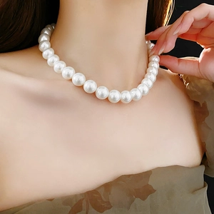 Gros plan d'un collier de perles blanches rondes porté pour un look très élégant