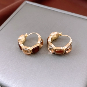 Close-up of vintage gold huggie earrings with champagne crystals on silk