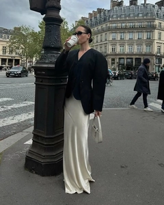 Détail d'une jupe longue élégante en satin de soie blanc perle avec blazer noir oversize