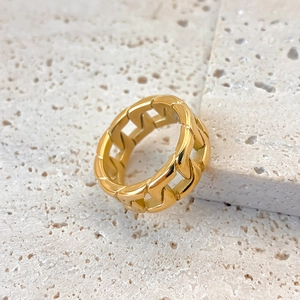 Detailed close-up of a polished gold-plated stainless steel curb link chain ring on stone