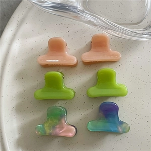 Mini acetate hair clips in colorful pastel shades displayed on a ceramic tray