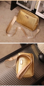 Close-up of golden wavy texture crossbody bag with wide beige strap and metallic plate