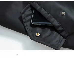 Detail einer großen taktischen Tasche an einer schwarzen Fliegerjacke mit Silberdruckknopf