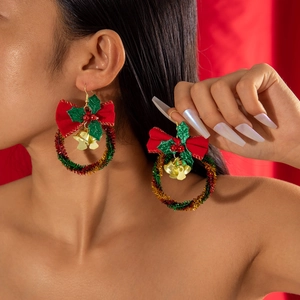 Close-up of Christmas wreath earrings with red bows and gold bells on model