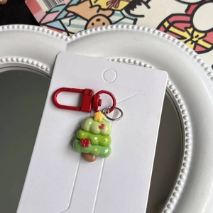 Detail of a Christmas tree keychain in green resin on white fashion jewelry card