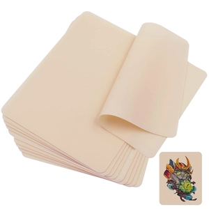 Stack of beige silicone tattoo practice skin sheets with a sample colorful tattoo design