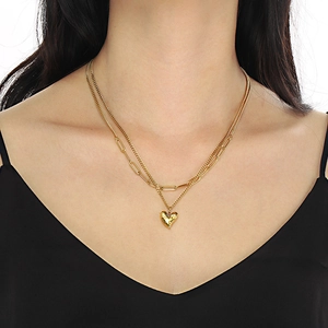 Gros plan d'un collier double rang doré avec chaîne trombone et pendentif cœur sur un mannequin