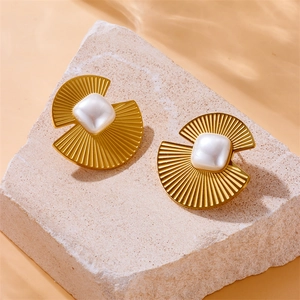 Golden fan-shaped square pearl stud earrings displayed on a textured stone surface