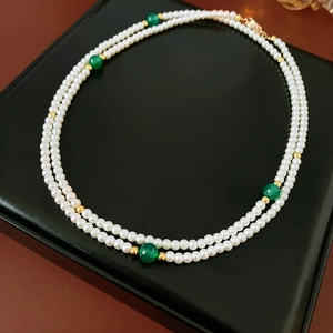 Close-up of double-layer faux pearl and green agate necklace on premium black display tray