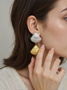 Détail de boucles d'oreilles coquillage bicolores avec texture fine sur un mannequin