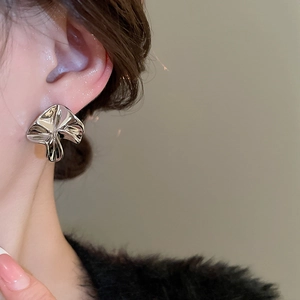 Close-up of silver irregular pleated mushroom earrings on ear with metallic mirror finish