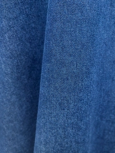 Dettaglio del tessuto denim blu scuro che mostra la trama verticale e l'armatura del vestito