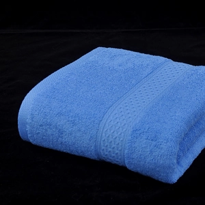 Soft blue cotton bath towel with textured terry loops folded on a black background