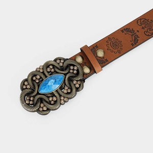 Detail of vintage brown leather belt featuring an ornate bronze buckle with a blue gemstone