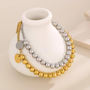 Détail du bracelet perlé en or 18 carats et argent sur un vase en céramique blanche
